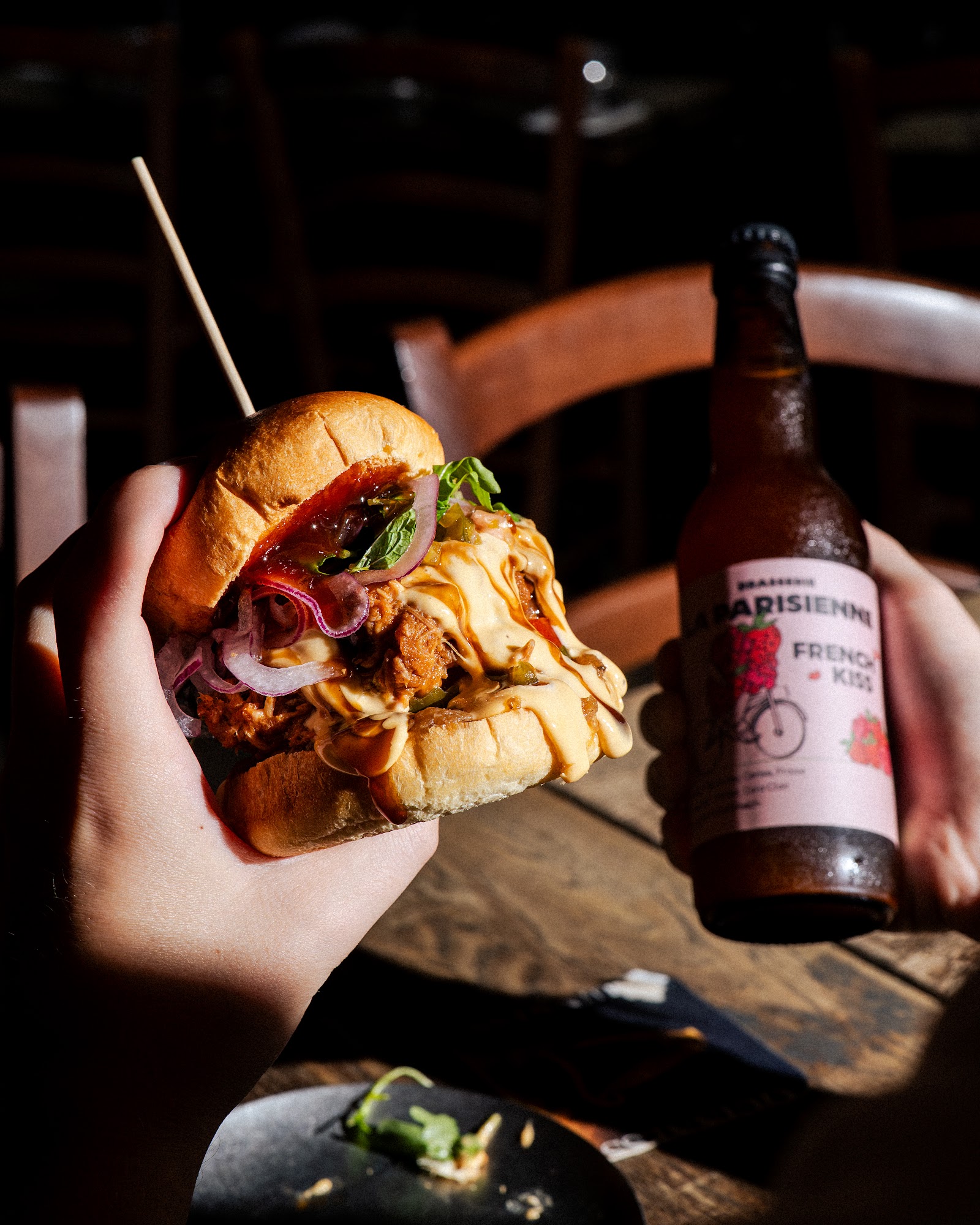Burger tenu en main avec une bière