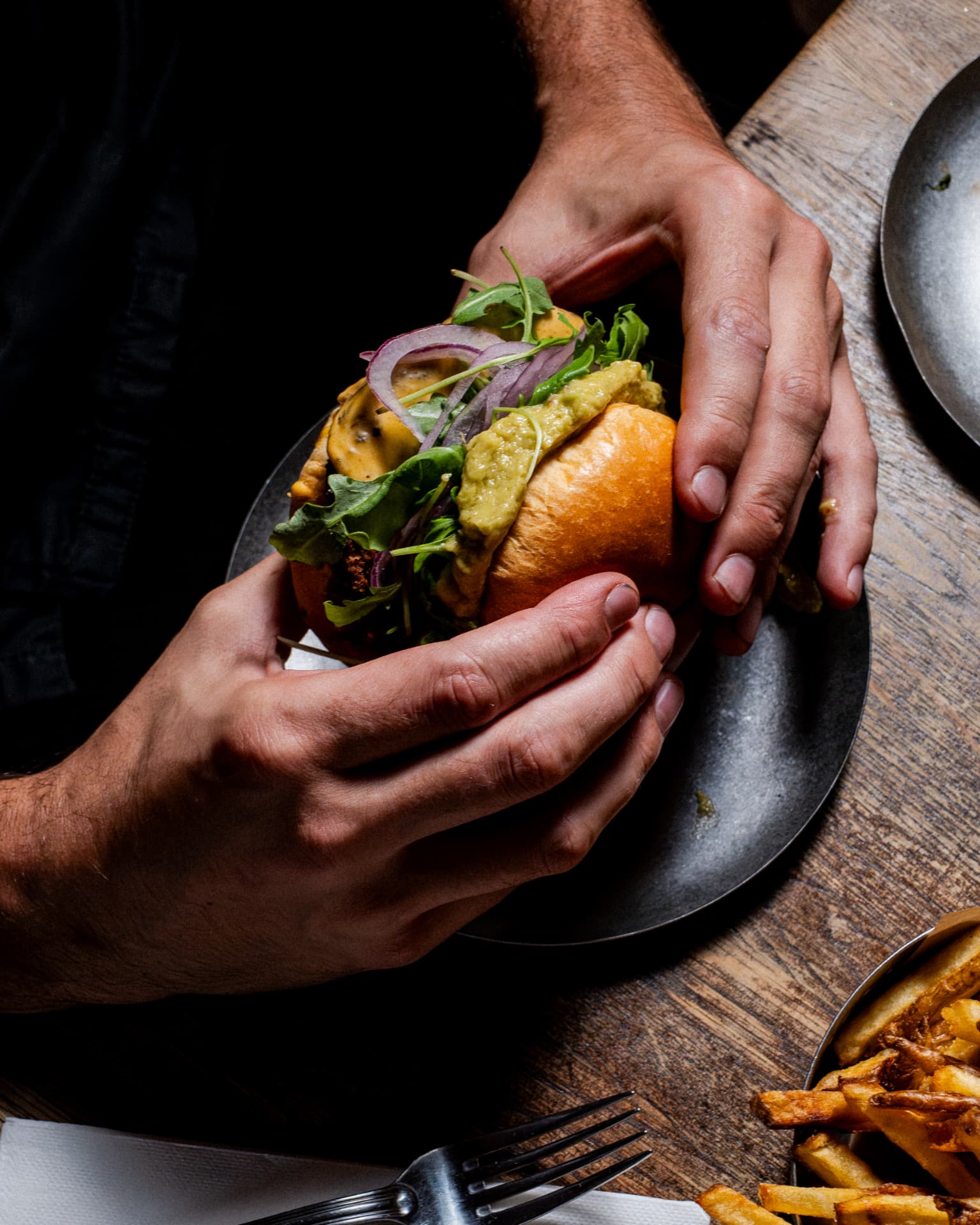 Burger tenu à deux mains avec frites maison