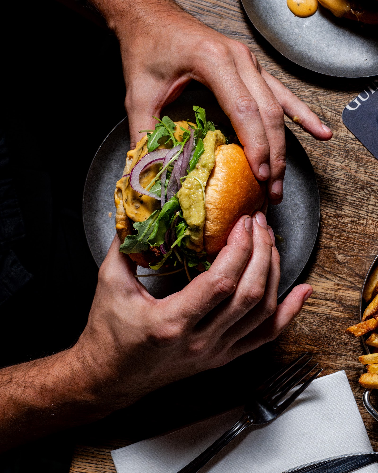 Burger tenu au-dessus de l'assiette