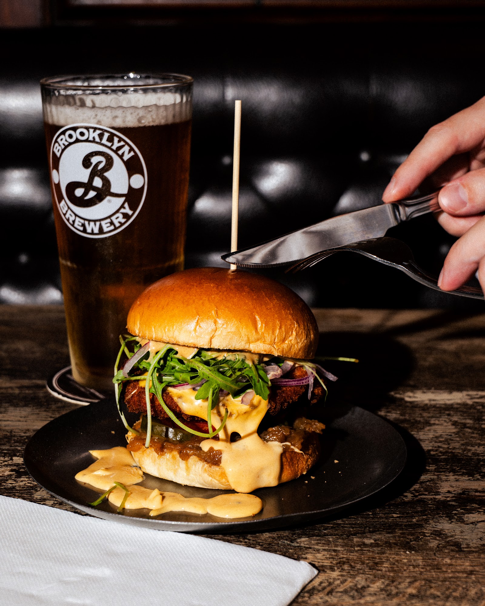 Burger découpé au couteau avec une bière